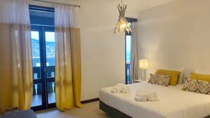 Habitación de hotel con cama, mesita de noche, lámpara y vista por la puerta.