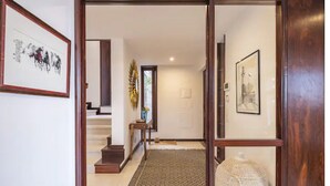 Un pasillo con puerta de madera, una escalera y una alfombra.