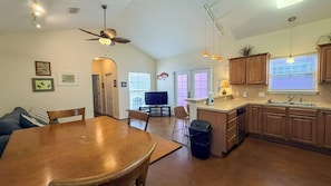 Une cuisine spacieuse avec des meubles en bois, un coin repas comprenant une table et des chaises, et un ventilateur de plafond.