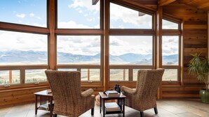 Una habitación con dos sillones de mimbre orientados a un gran ventanal con vistas a la montaña.