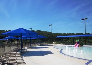 Een waterpark met blauwe parasols, een zwembad en een glijbaan.
