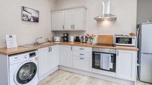 A modern kitchen with white cabinets, a washing machine, a microwave, and a toaster.