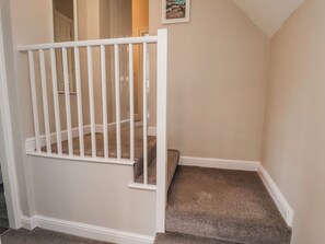 A staircase with a white railing, carpeted steps, and a door at the top.