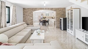 Een moderne woonkamer met een beige hoekbank, een witte salontafel en een keuken op de achtergrond.