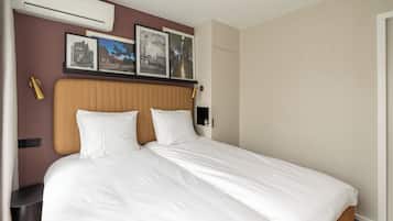 Una cama bien hecha con ropa de cama blanca, cabecera con panel de madera y aire acondicionado instalado en la pared.