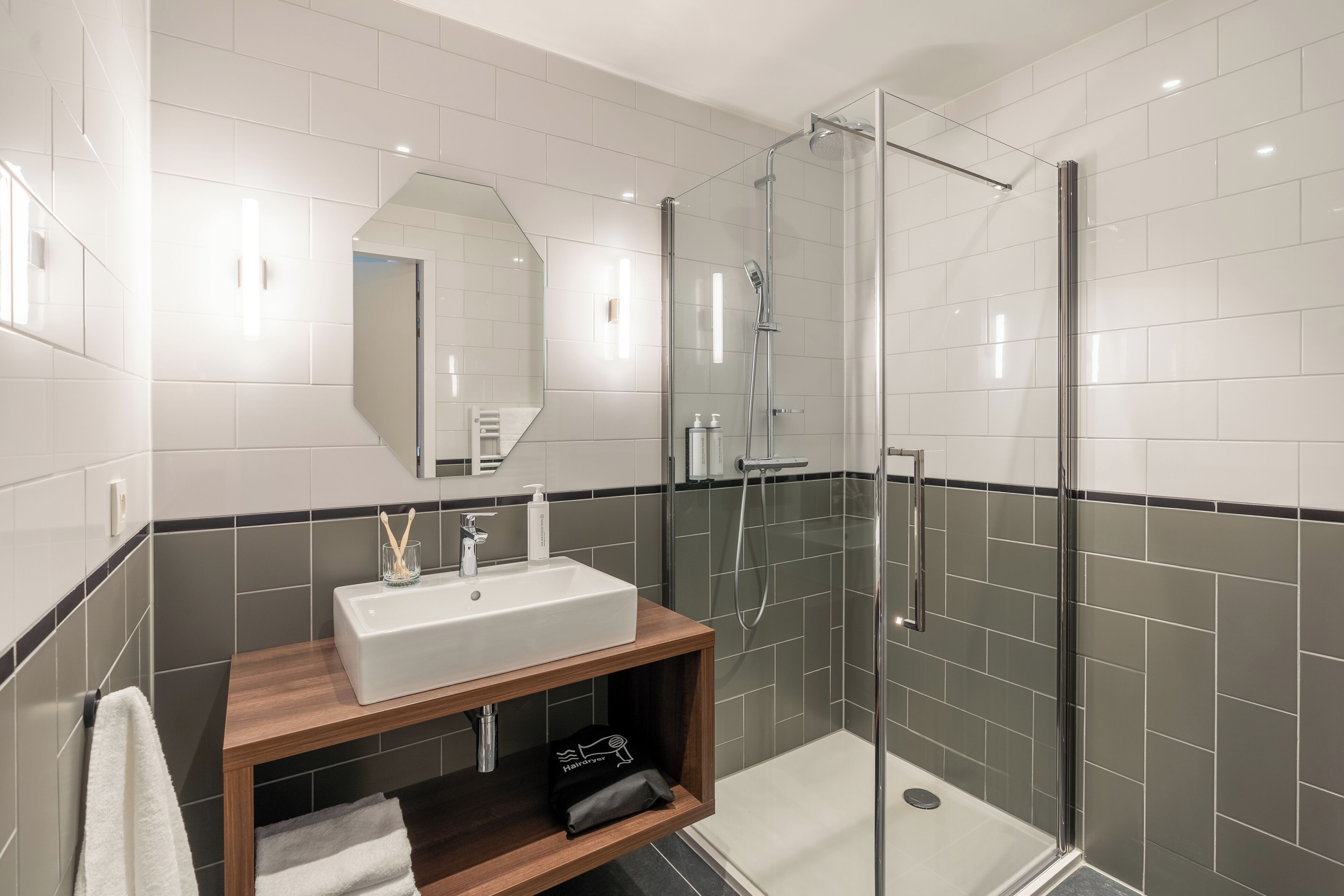 A modern bathroom with a glass-enclosed shower, a wooden vanity with a white sink, and a large mirror.