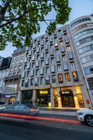 Un edificio de varios pisos con un estilo arquitectónico moderno, que destaca un llamativo rótulo 'Brico' en la planta baja.