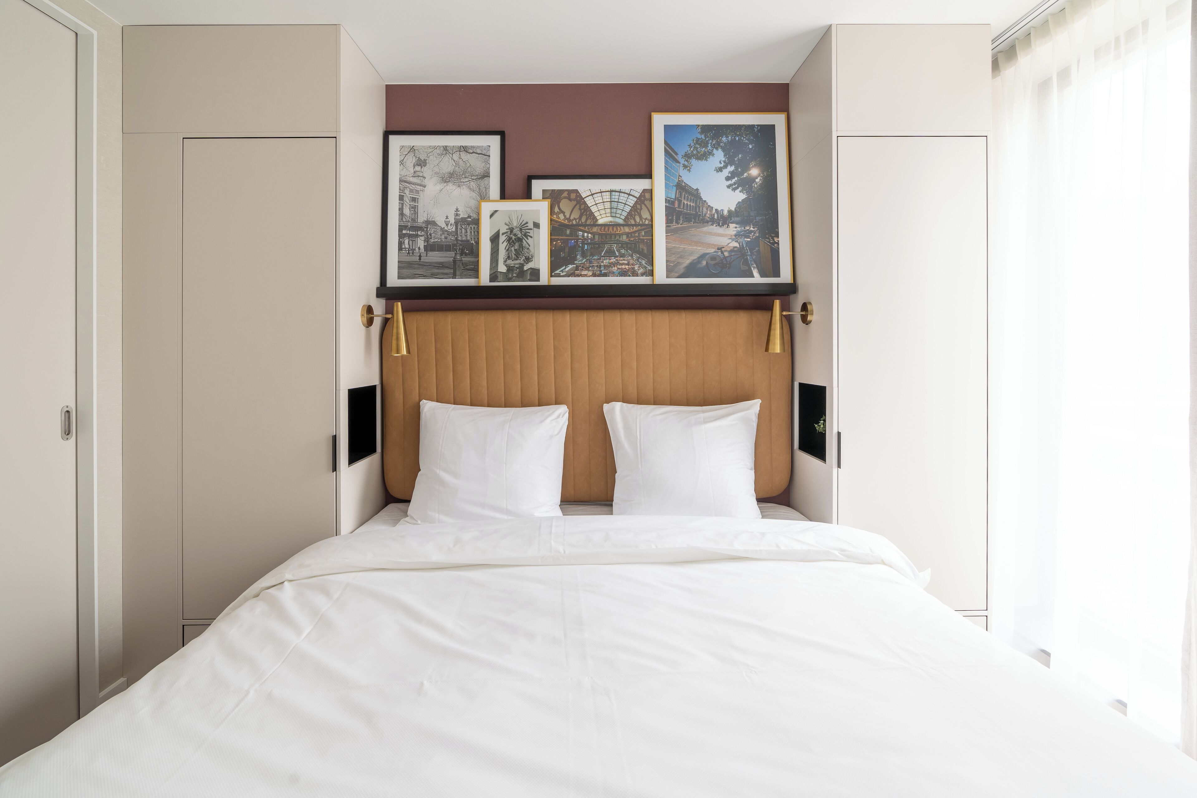 Una habitación de hotel con una cama grande, un cabecero de madera y cuadros enmarcados en la pared.