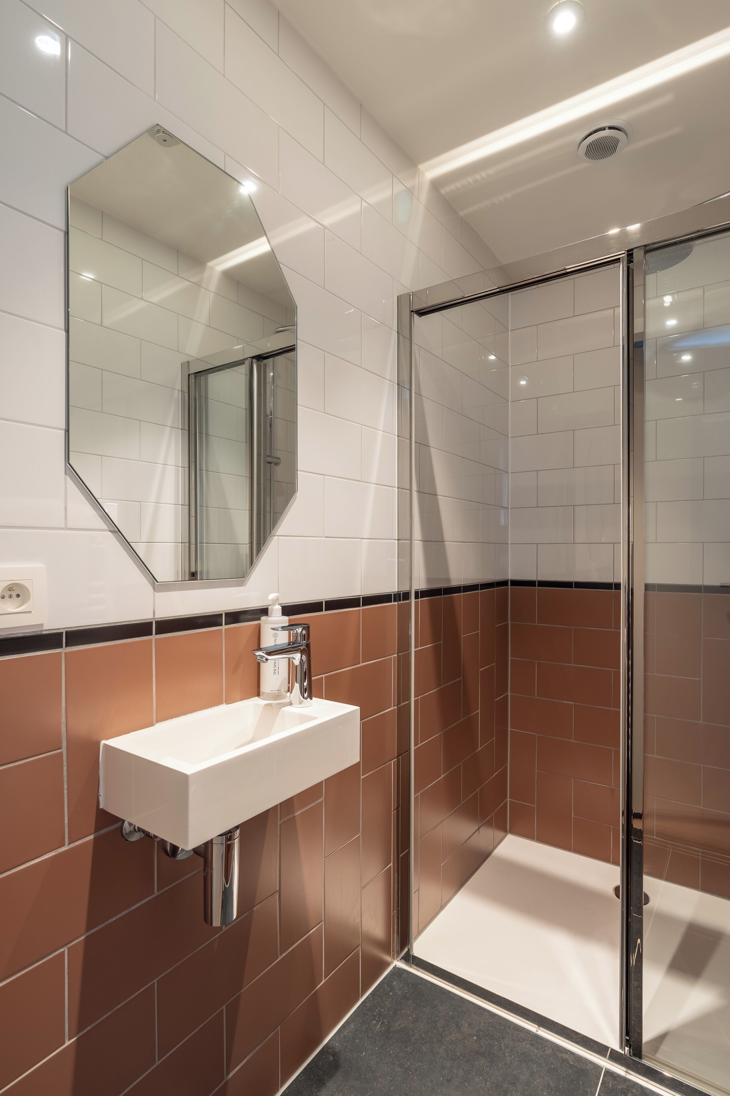 A modern bathroom with a white sink, a glass shower enclosure, and a mirror on the wall.