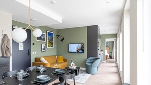Una sala de estar moderna con comedor, un sofá, un televisor y una silla azul.