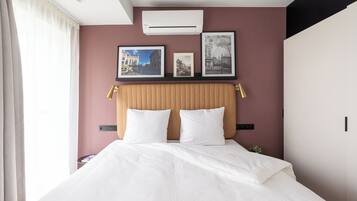 Una habitación de hotel con una cama, cabecera y cuadros en la pared.