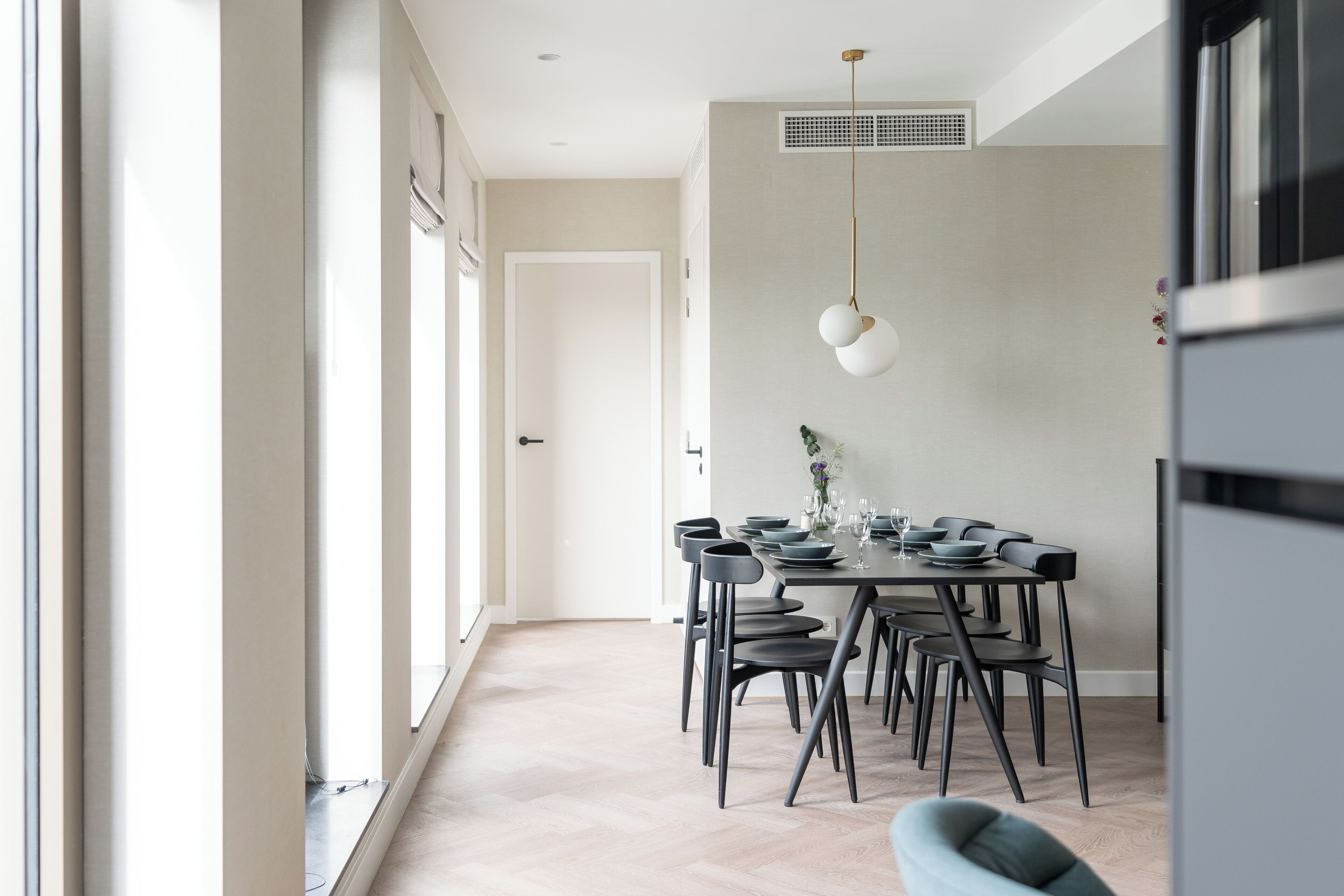 Un espace repas moderne avec un plancher en bois clair, une table en bois foncé et des chaises noires.