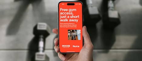 A hand holding a smartphone displaying an advertisement for a gym.