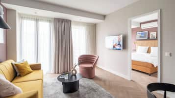 A modern hotel room with a sofa, armchair, and a bed.