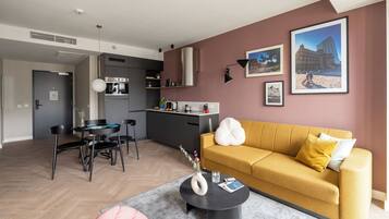 Una sala de estar moderna con un sofá amarillo, una mesa de comedor y una cocina al fondo.