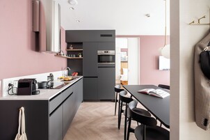 Una cocina moderna con armarios grises, horno empotrado y comedor con mesa y sillas.