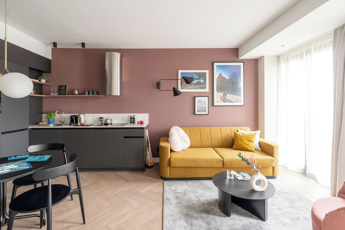 Un saló modern amb un sofà groc, una taula de centre i una zona de menjador amb taula i cadires.