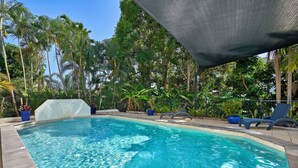 Une piscine à l’eau d’un bleu cristallin, entourée d’une végétation luxuriante et de palmiers.