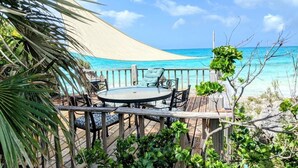 Une terrasse en bois avec une table et des chaises donnant sur une plage.