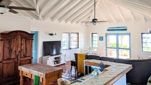Un vaste espace de vie doté d’un plafond haut, d’un meuble en bois, d’un téléviseur, d’un canapé et d’une table à manger.