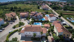 Une vue aérienne d’un quartier résidentiel avec plusieurs maisons, une piscine et une route.