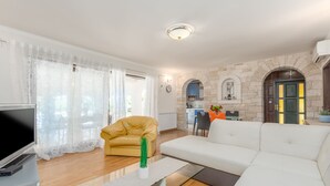 Un salon moderne avec un canapé, un fauteuil jaune, une table basse en verre et un téléviseur à écran plat.