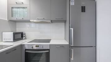 A compact kitchen with a built-in microwave, oven, and refrigerator.
