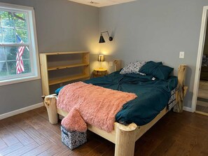A bedroom with a wooden bed frame, a pink fluffy throw, and a patterned pillow.
