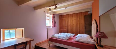 A bedroom with a bed, a window, a desk, and a radiator.