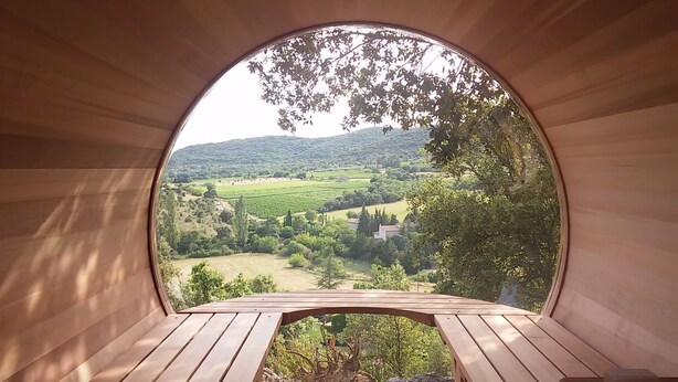 Une structure circulaire en bois, dotée d’un banc et offrant une vue sur un paysage verdoyant.