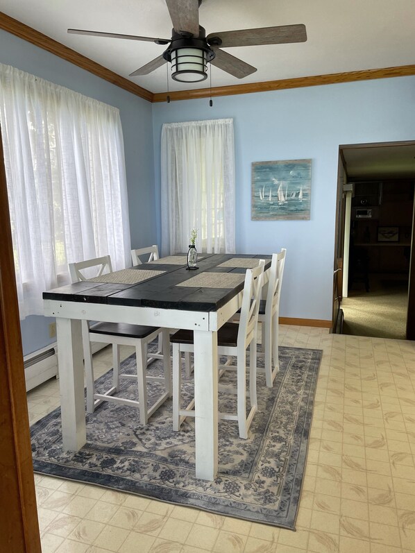 Un coin repas avec une table et des chaises, un ventilateur de plafond et un tableau accroché au mur.