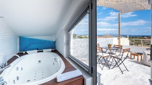 Un baño moderno con una bañera grande, vistas al exterior y un patio con mesa y sillas.