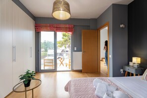 A bedroom with a bed, a bedside table with a lamp, a potted plant, a sliding glass door to a balcony, and a view of the outside. - EVAERI villa - Tranquil getaway! (Artemis)
