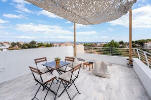 A rooftop terrace with a table and chairs, a white chair, a small table with a plant, and a white sofa. - EVAERI villa - Tranquil getaway! (Artemis)