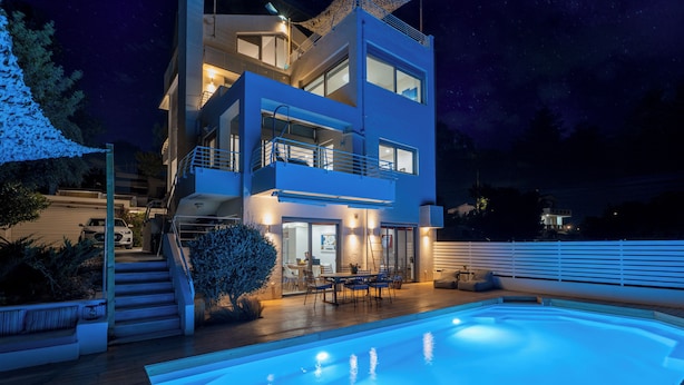 Una casa moderna de dos pisos con piscina, mobiliario exterior y una escalera que lleva al nivel superior.