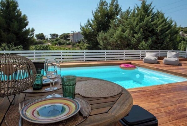A wooden deck with a pool, surrounded by a white fence and trees. - EVAERI villa - Tranquil getaway! (Artemis)
