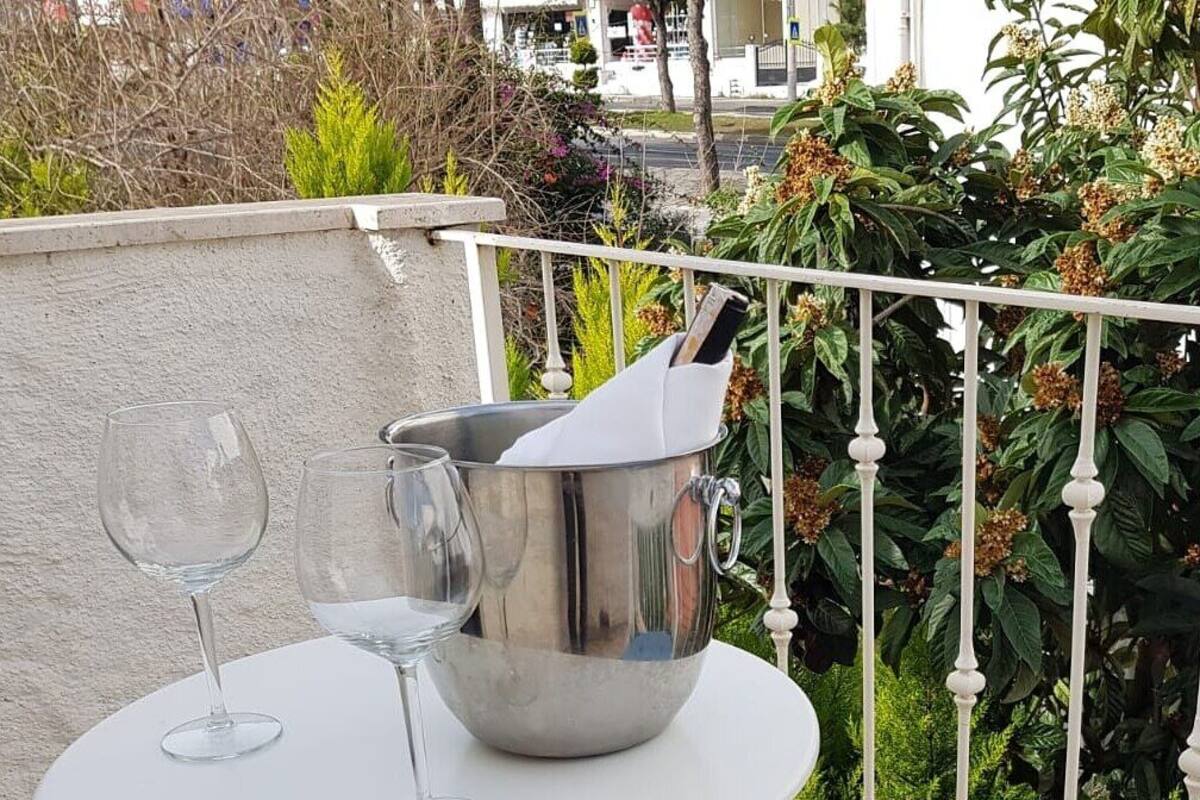 A small round table with two wine glasses and a metal bucket on a balcony.