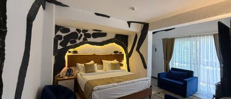 A bedroom with a large bed, a nightstand, a blue sofa, and a window with curtains.