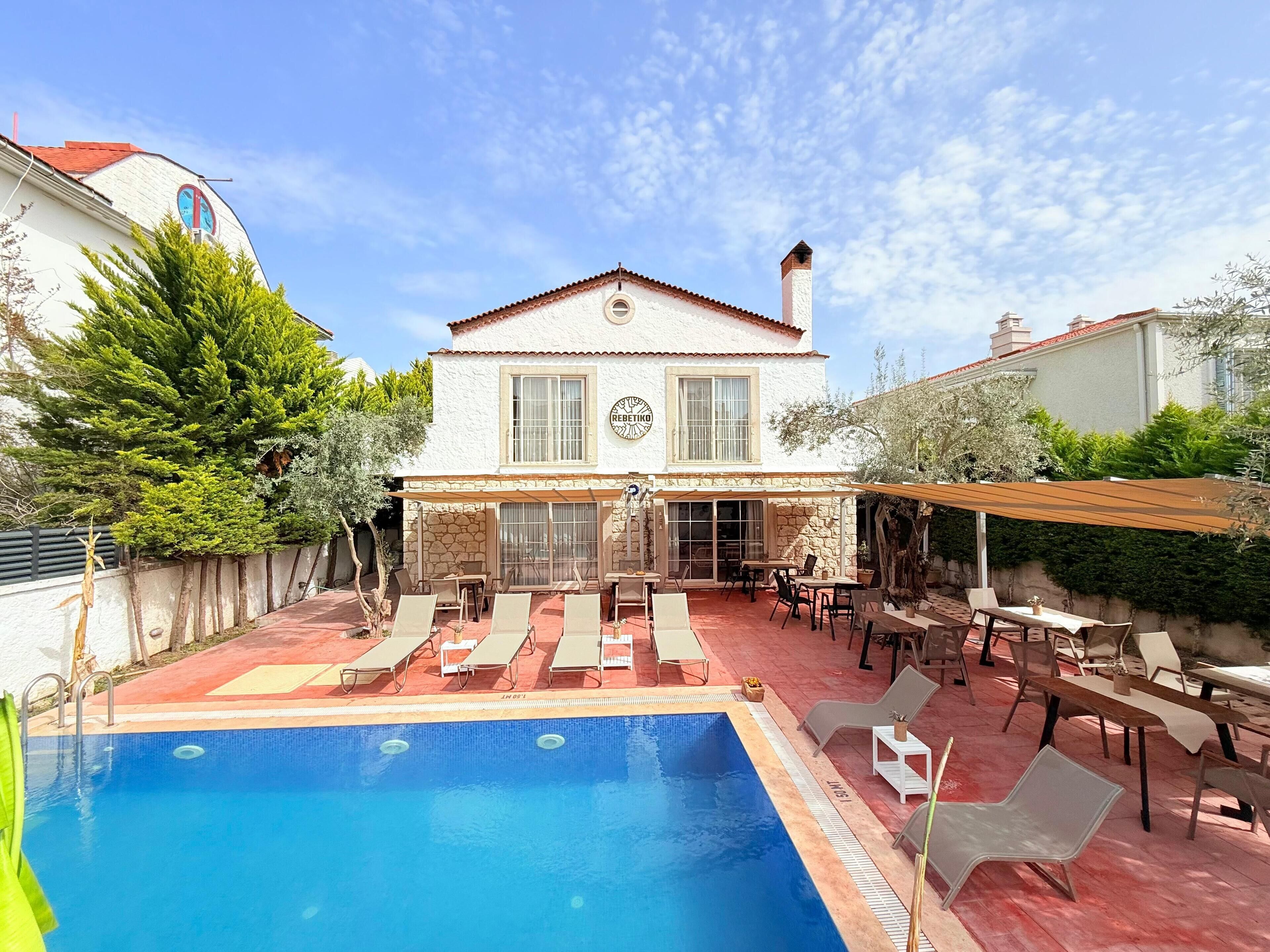 A two-story house with a swimming pool, outdoor seating, and a garden.