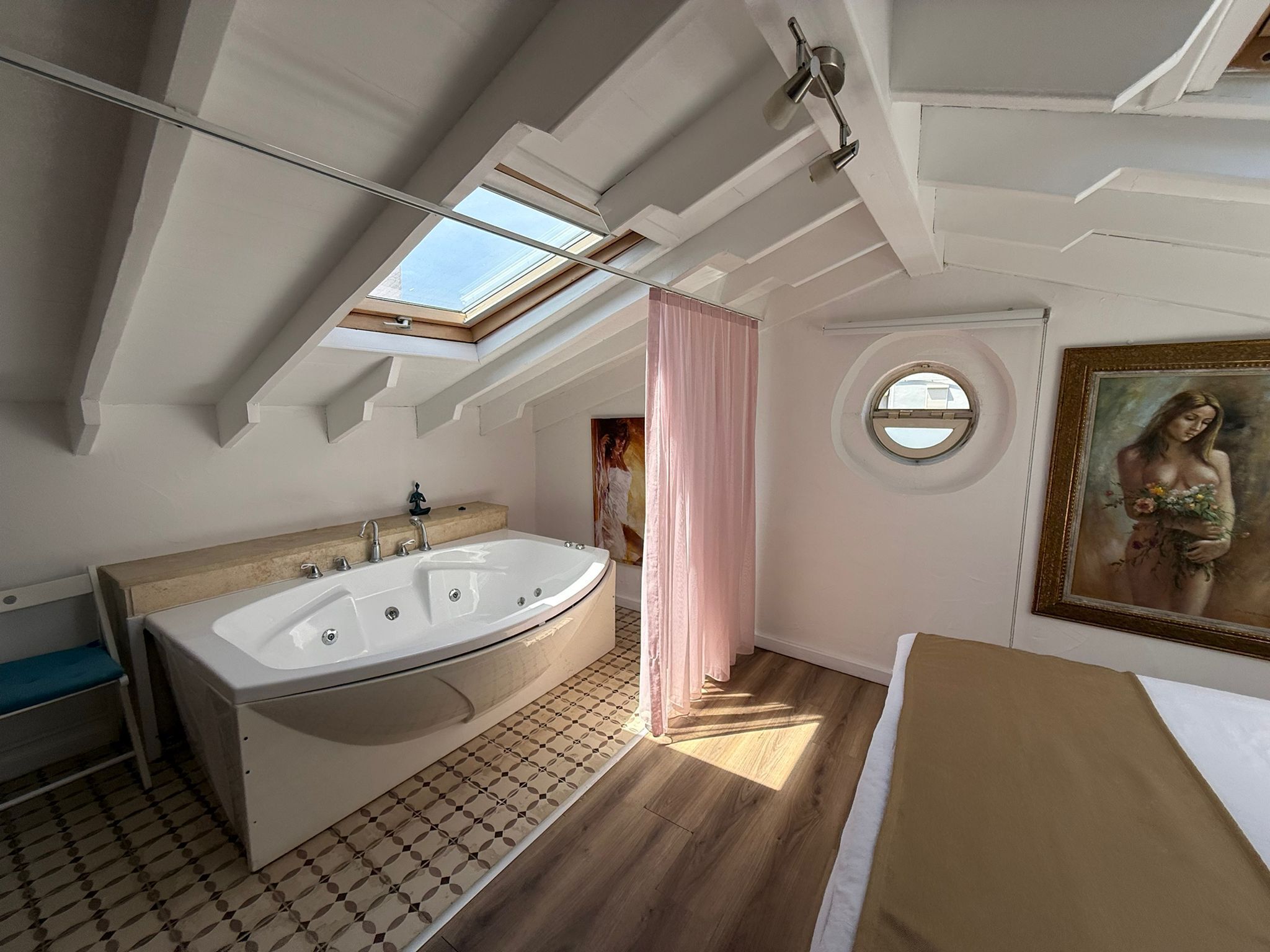 Une salle de bain moderne avec une baignoire sur pieds, un puits de lumière et une fenêtre ronde.