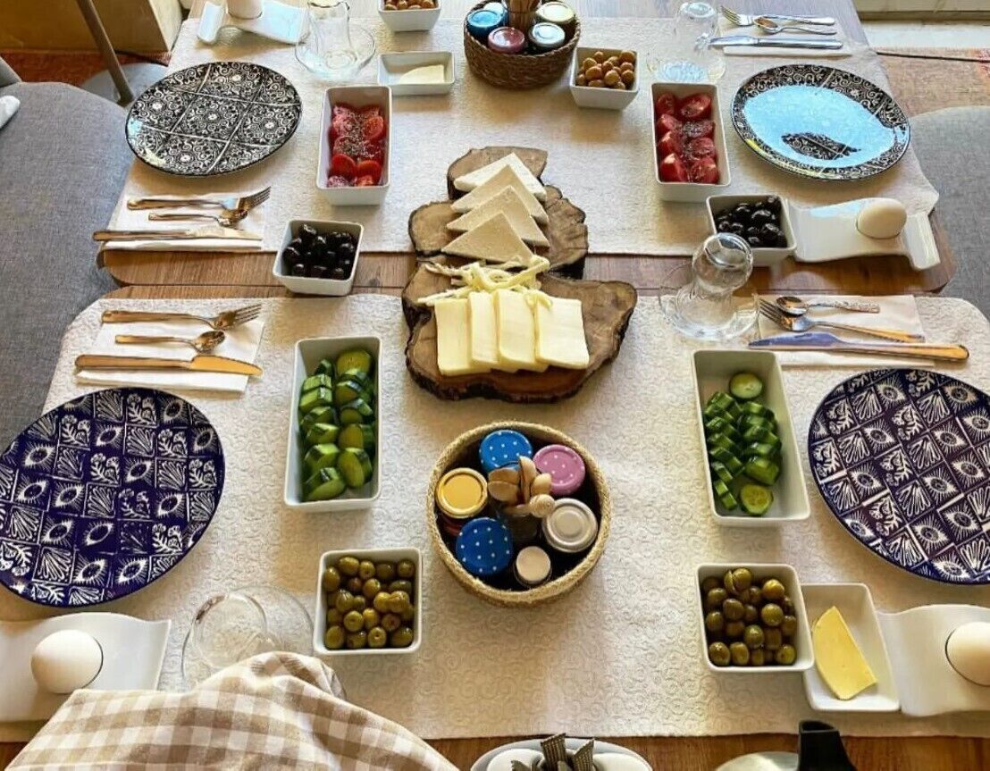 Una mesa dispuesta para una comida con varios quesos, aceitunas y pan.