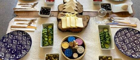 Una mesa dispuesta para una comida con varios quesos, aceitunas y pan.