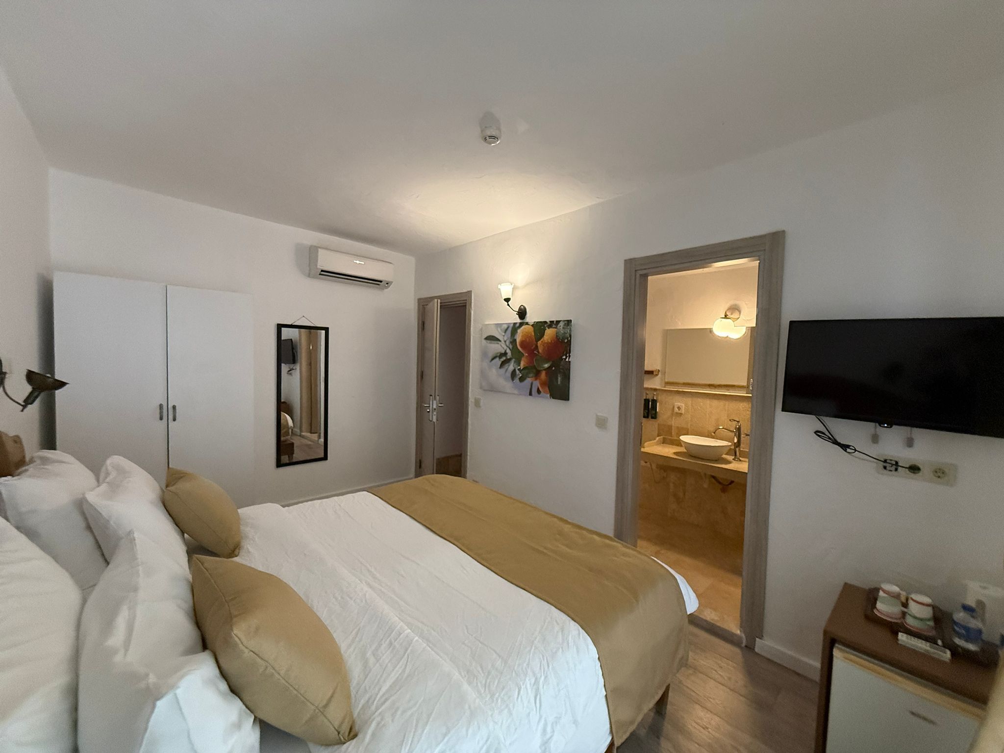 Camera da letto con un letto, un armadio, un condizionatore, una televisione e un bagno visibile tramite una porta aperta.