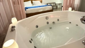 A modern bathroom with a large bathtub, a wooden headboard bed, and a skylight. - Alaçatı Otel Rebetiko (Cesme)