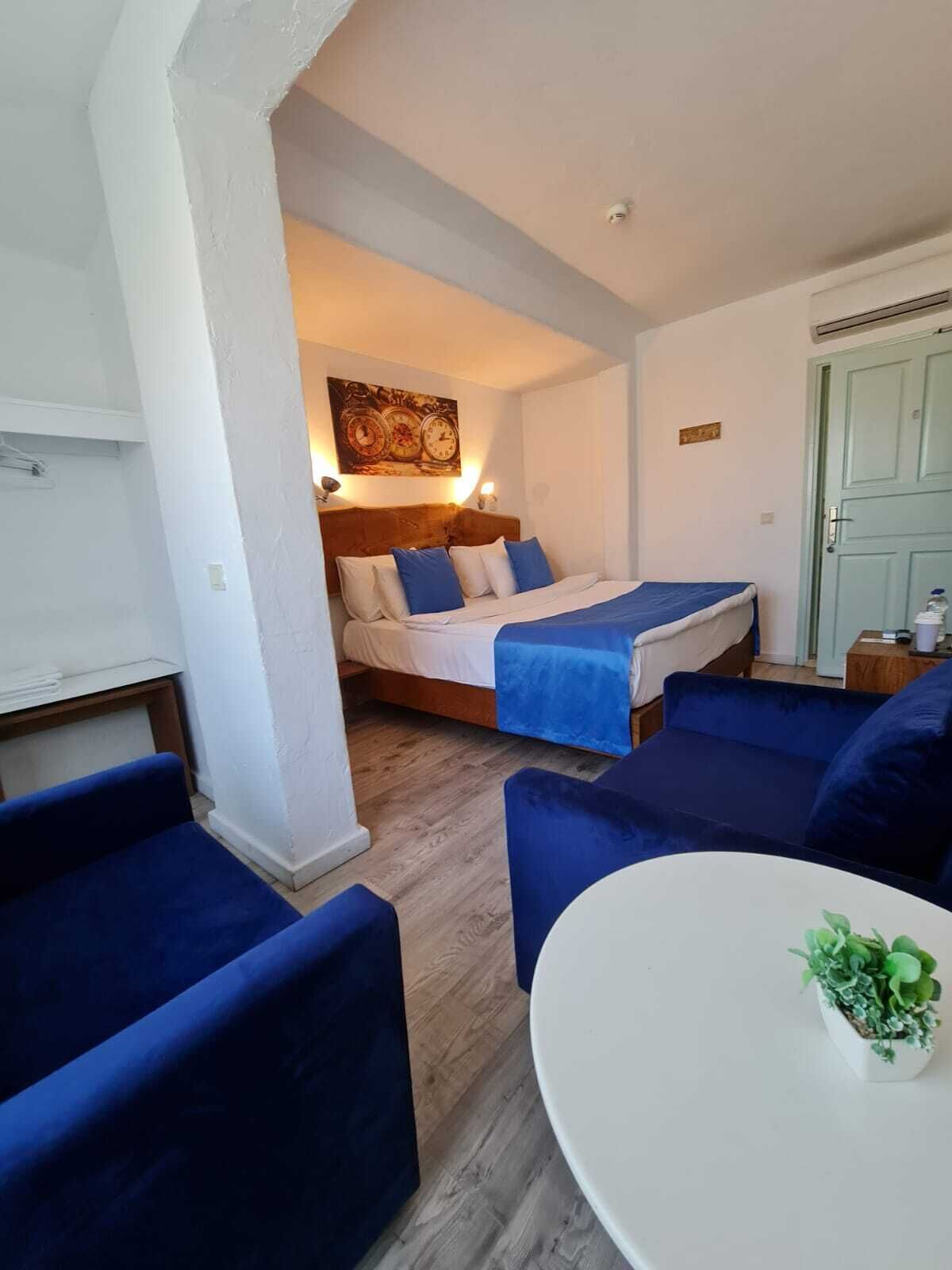A cozy room with a bed, a round table, and blue sofas.