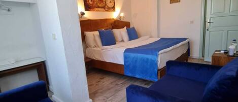 A cozy room with a bed, a round table, and blue sofas.
