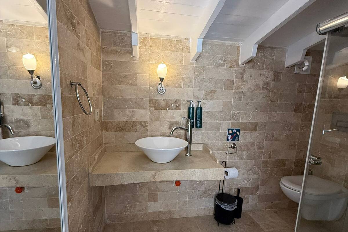 A bathroom with two sinks, a toilet, a shower, and a glass-enclosed shower area.