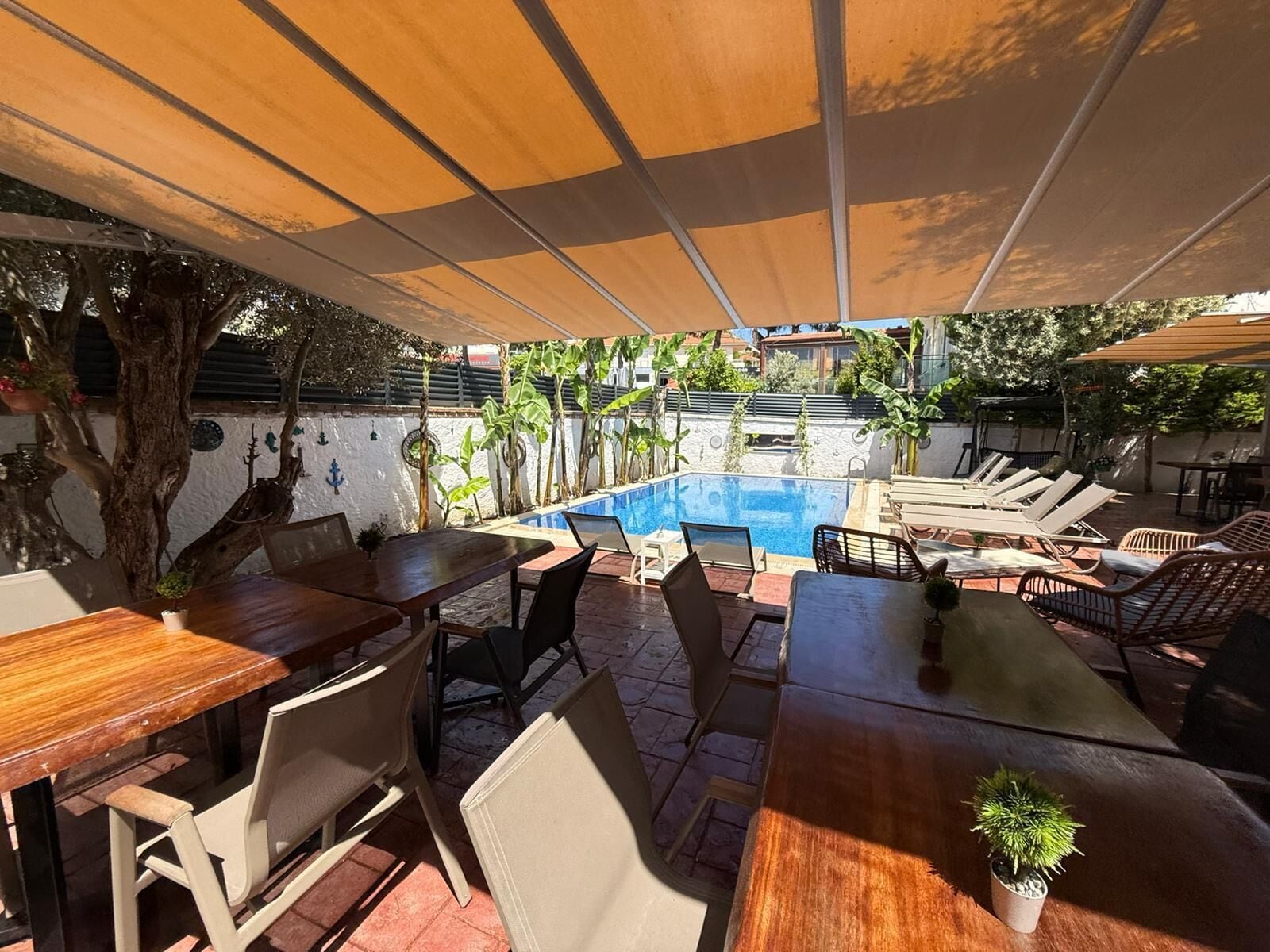 A poolside area with a wooden table, chairs, and a small potted plant.