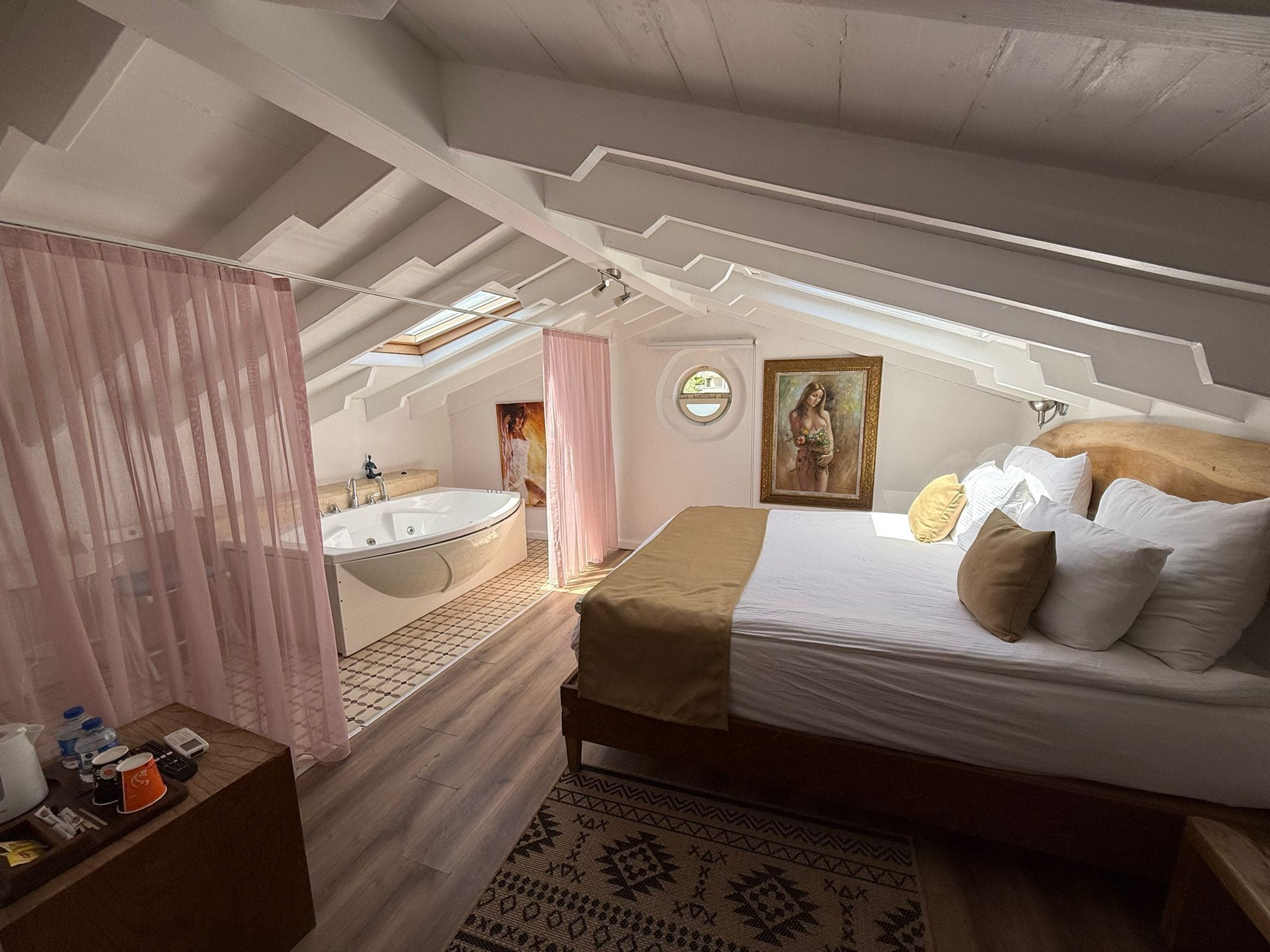 Une chambre avec un grand lit, une salle de bain avec une baignoire et une fenêtre de toit.