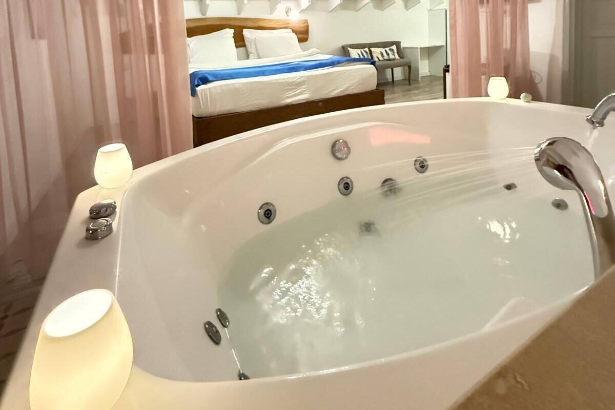 A modern bathroom with a freestanding bathtub, a skylight, and a bed with a view of the sky.